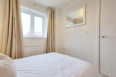 a white bedroom with a bed and a window at Luxury and cosy 2 bed entire house in Essex 20 mins from beach in Colchester