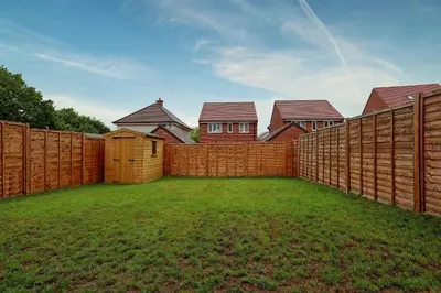 a fence in a yard with houses behind it at Luxury and cosy 2 bed entire house in Essex 20 mins from beach in Colchester