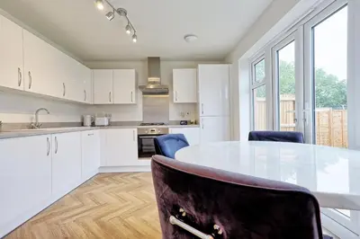 a kitchen with white cabinets and a table and chairs at Luxury and cosy 2 bed entire house in Essex 20 mins from beach in Colchester