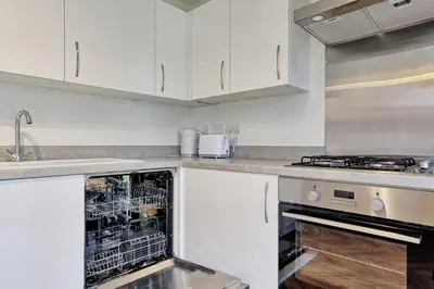 a kitchen with white cabinets and an open dishwasher at Luxury and cosy 2 bed entire house in Essex 20 mins from beach in Colchester