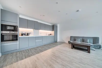 a kitchen with white cabinets and a couch and a table at Peaceful and stylish apartment near Cambridge with parking in CBG