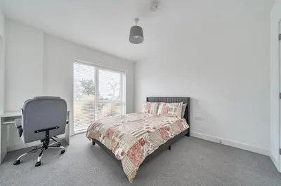 a bedroom with a bed and a desk and a chair at Peaceful and stylish apartment near Cambridge with parking in CBG