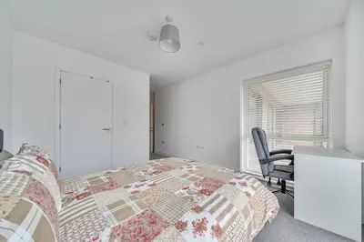 a bedroom with a bed and a desk and a chair at Peaceful and stylish apartment near Cambridge with parking in CBG