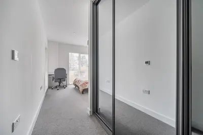 a mirror in a room with a bed and a chair at Peaceful and stylish apartment near Cambridge with parking in CBG