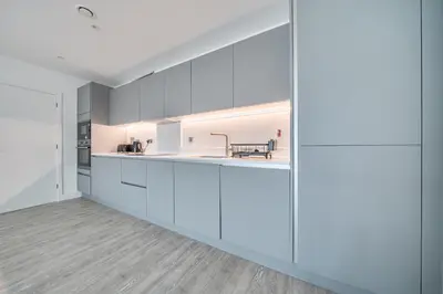 an open kitchen with white cabinets and a dining area at Peaceful and stylish apartment near Cambridge with parking in CBG
