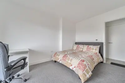 a bedroom with a bed and a desk and a chair at Peaceful and stylish apartment near Cambridge with parking in CBG