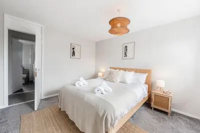 a white bedroom with a bed with two towels on it at 15 Mins to Sizewell C - Driveway Parking - Contractor Friendly - 2 Bedroom in Saxmundham