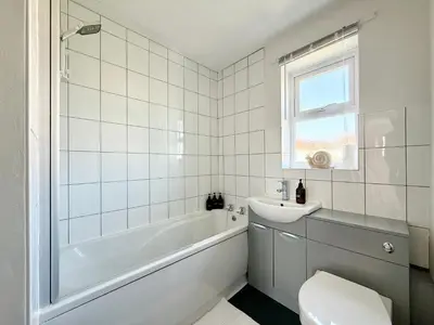 a white bathroom with a tub and a sink at 15 Mins to Sizewell C - Driveway Parking - Contractor Friendly - 2 Bedroom in Saxmundham