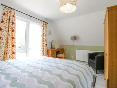 a bedroom with a bed and a chair and a window at Kingfisher in Ely