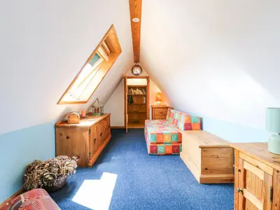 a attic room with a couch and a chair at Kingfisher in Ely