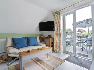 a living room with a couch and a sliding glass door at Kingfisher in Ely