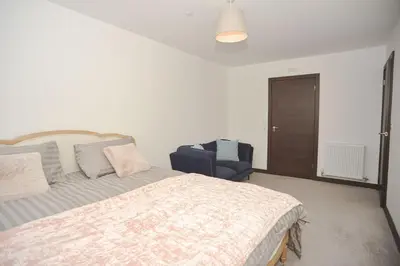 a bedroom with a bed and a chair in it at Seaview City Lodge , 2- bedroom flat with Parking in Southend-on-Sea