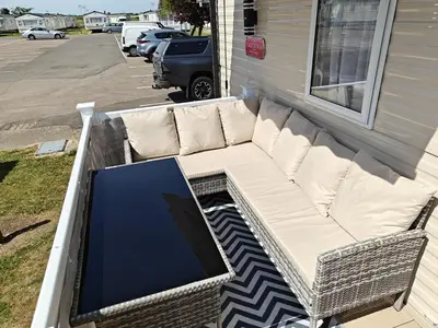 a couch sitting on the porch of a house at Family Holiday Home with private terrace in Saint Osyth