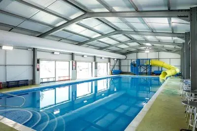 a large swimming pool with a slide in a building at Family Holiday Home with private terrace in Saint Osyth