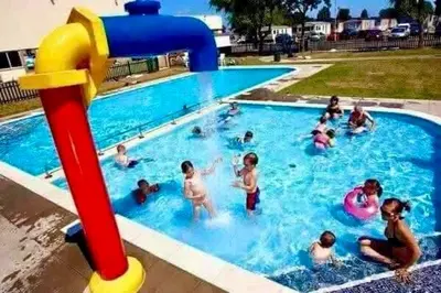 a group of people playing in a swimming pool at Family Holiday Home with private terrace in Saint Osyth