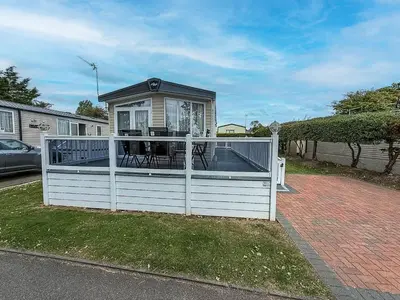 a house with a white fence with a deck at Stunning Caravan At West Mersea Park 75192Wm in West Mersea