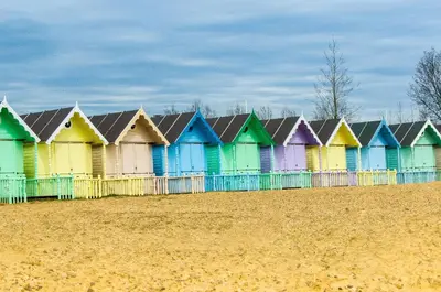 a row of colorful beach huts on a beach at Stunning Caravan At West Mersea Park 75192Wm in West Mersea