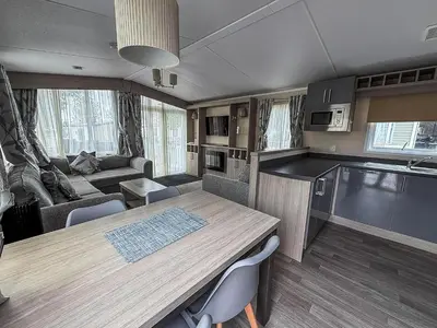 a kitchen and living room with a table and a couch at Stunning Caravan At West Mersea Park 75192Wm in West Mersea