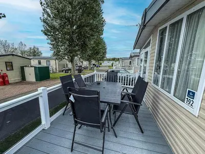 a wooden deck with a table and chairs on a house at Stunning Caravan At West Mersea Park 75192Wm in West Mersea