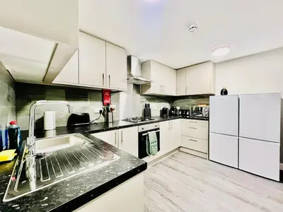 a kitchen with a sink and a white refrigerator at Quirky and spacious 5 Bedroom and 3 bathroom house Sleeps 7 with free Parking in Basildon in Laindon