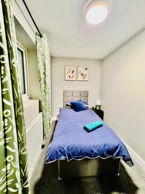 a bedroom with a bed with a blue comforter at Quirky and spacious 5 Bedroom and 3 bathroom house Sleeps 7 with free Parking in Basildon in Laindon