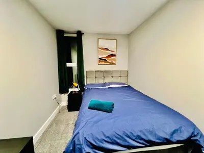 a bedroom with a large bed with a blue comforter at Quirky and spacious 5 Bedroom and 3 bathroom house Sleeps 7 with free Parking in Basildon in Laindon