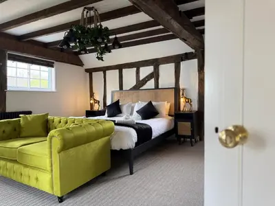a bedroom with a bed and a green couch at Family stay with soft play, hot tub, ping pong, pool table! in Hythe