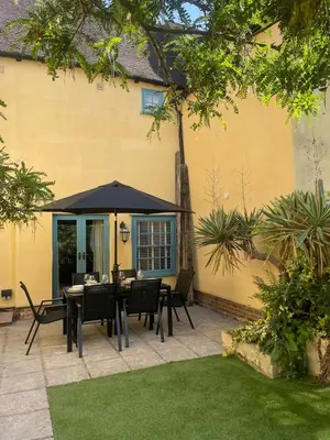 a patio with a table and chairs under an umbrella at Family stay with soft play, hot tub, ping pong, pool table! in Hythe