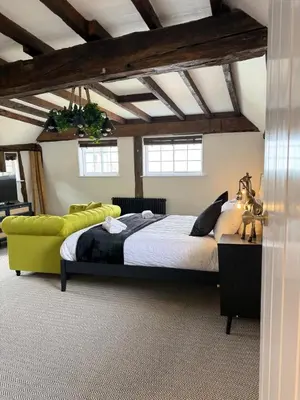 a bedroom with a large bed and a yellow couch at Family stay with soft play, hot tub, ping pong, pool table! in Hythe