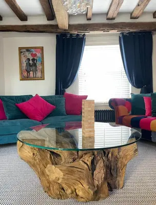 a living room with a tree stump coffee table at Family stay with soft play, hot tub, ping pong, pool table! in Hythe