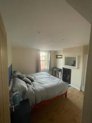 a bedroom with a bed and a desk in it at Cottage of Content in Wivenhoe