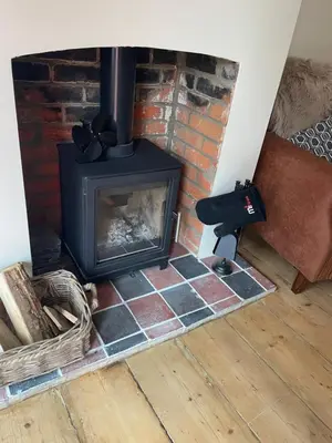 a brick fireplace with a stove in a room at Cottage of Content in Wivenhoe