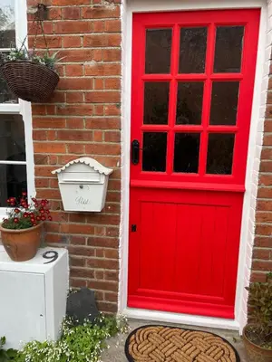 a red door on the side of a brick house at Cottage of Content in Wivenhoe