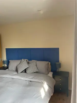 a bed with a blue headboard in a bedroom at Cottage of Content in Wivenhoe