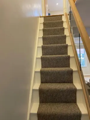a staircase with brown carpet and wooden railings at Cottage of Content in Wivenhoe