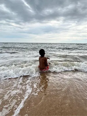 a young boy sitting in the water at the beach at Verb View 6 Berth Caravan St Osyth Clacton-On-Sea in Saint Osyth