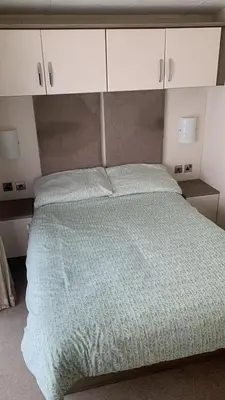 a bed with a green comforter in a bedroom at Verb View 6 Berth Caravan St Osyth Clacton-On-Sea in Saint Osyth