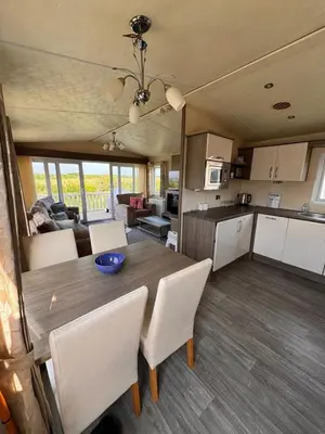 a kitchen and dining room with a table and chairs at Verb View 6 Berth Caravan St Osyth Clacton-On-Sea in Saint Osyth