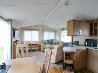 a kitchen and living room with a couch and a table at Bluebird in Clacton-on-Sea