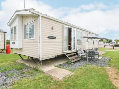 a tiny house with a patio and an umbrella at Bluebird in Clacton-on-Sea