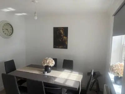 a dining room with a table and a clock on the wall at Upto 9 Contractors, LongStay Discounts in Hythe