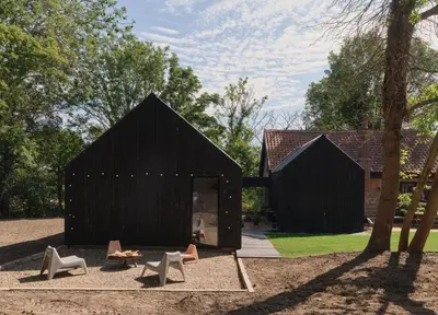 two black wooden buildings with chairs in a yard at The Church Hall in Ipswich