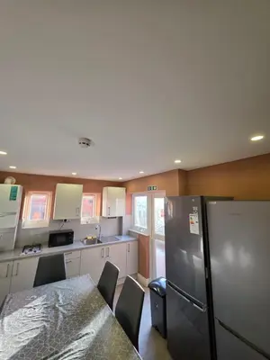 a kitchen with a table and a refrigerator at ELY Stay in Ipswich
