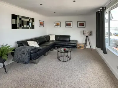 a living room with a black leather couch and a window at Thirslet in Maldon