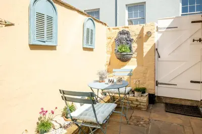 a patio with a table and chairs next to a building at Seahorse Cottage, Aldeburgh - sleeps 4 - Adult only property - Managed by Aldeburgh Coastal Cottages in Aldeburgh