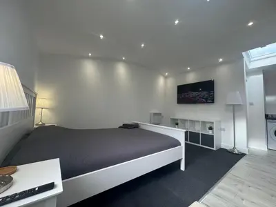 a bedroom with a bed and a tv on the wall at The Studio Guesthouse in Little Burstead