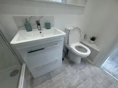 a white bathroom with a toilet and a sink at The Studio Guesthouse in Little Burstead