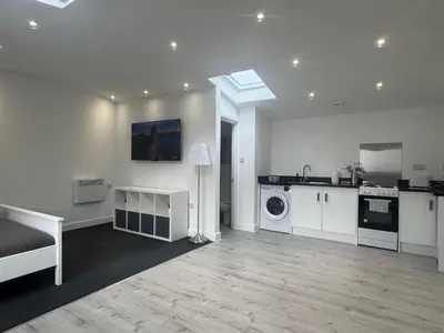 a white room with a kitchen and a washing machine at The Studio Guesthouse in Little Burstead