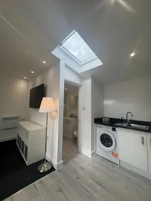 a bathroom with a washing machine and a window at The Studio Guesthouse in Little Burstead