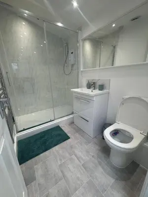 a bathroom with a shower and a toilet and a sink at The Studio Guesthouse in Little Burstead